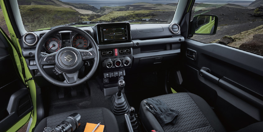 Interior del Suzuki Jimny, mostrando el volante, el panel de instrumentos y la pantalla de infoentretenimiento.
